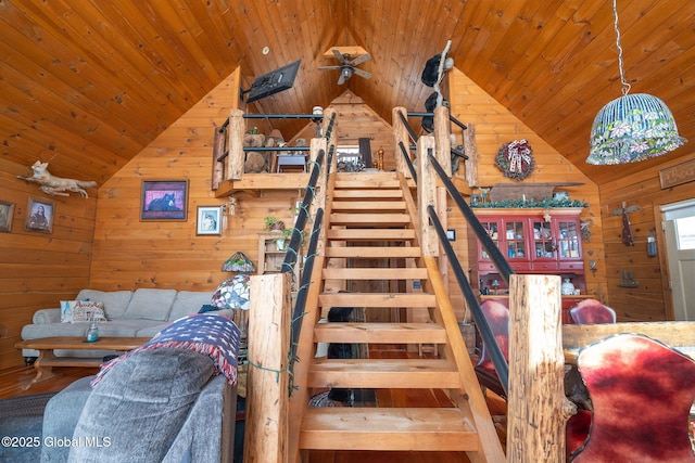 staircase with wooden ceiling, vaulted ceiling, and wooden walls