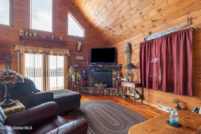 living area featuring wooden ceiling, a healthy amount of sunlight, wood walls, and a stone fireplace