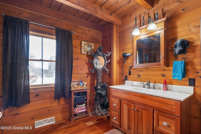 bathroom featuring visible vents, wood walls, and beamed ceiling