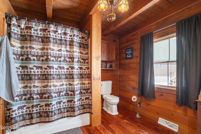 bathroom with visible vents, toilet, wooden walls, wooden ceiling, and beamed ceiling