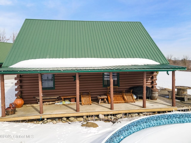 snow covered property featuring a deck, metal roof, and log siding