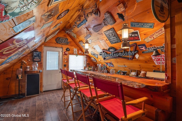 bar with hardwood / wood-style floors, vaulted ceiling, wooden walls, and a dry bar