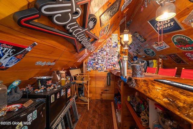 interior space with lofted ceiling, dark wood-type flooring, and wood walls