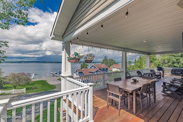 wooden deck with a water view and outdoor dining space