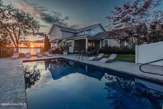 back of house at dusk with a patio area, fence, and a fenced in pool