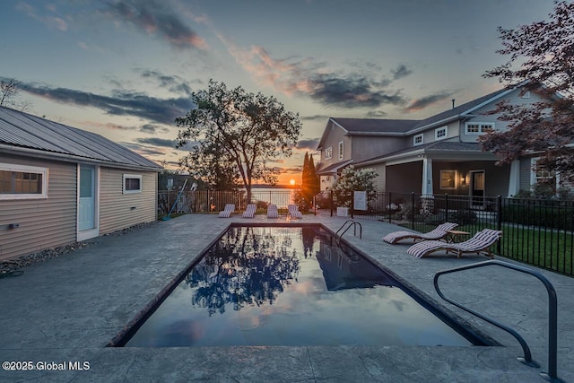 pool at dusk with a patio, a fenced backyard, and a fenced in pool