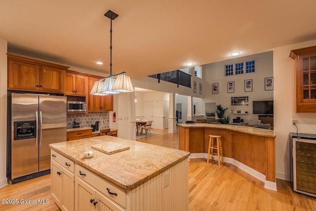 kitchen featuring appliances with stainless steel finishes, brown cabinetry, light wood finished floors, and tasteful backsplash