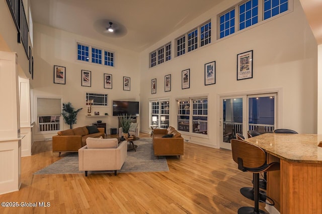 living area with light wood-type flooring and a towering ceiling