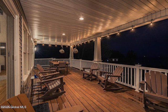 deck at night featuring outdoor dining area