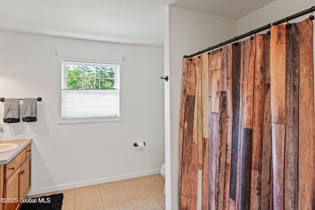 bathroom featuring toilet, vanity, a shower with curtain, baseboards, and tile patterned floors