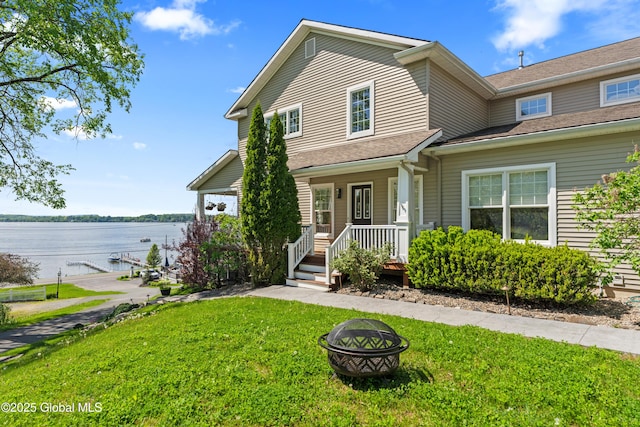 view of front of property with a fire pit, a porch, a front yard, and a water view