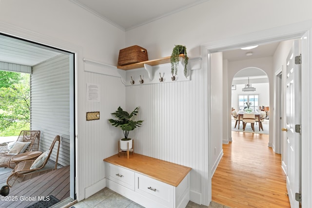 mudroom featuring light wood finished floors, arched walkways, and ornamental molding