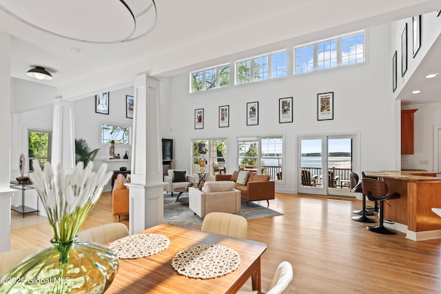 dining area featuring light wood-type flooring, a wealth of natural light, and ornate columns