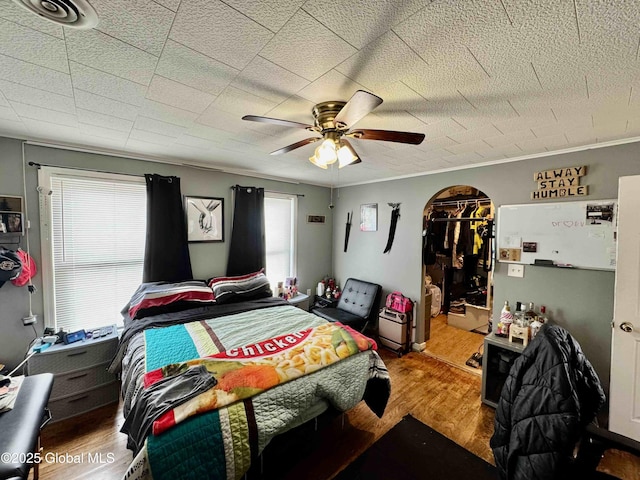 bedroom featuring ceiling fan, visible vents, wood finished floors, and ornamental molding