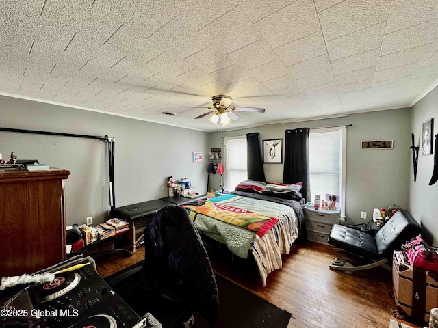 bedroom with ceiling fan, crown molding, and wood finished floors