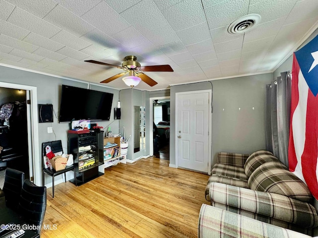 living room featuring crown molding, visible vents, light wood-style flooring, ceiling fan, and baseboards