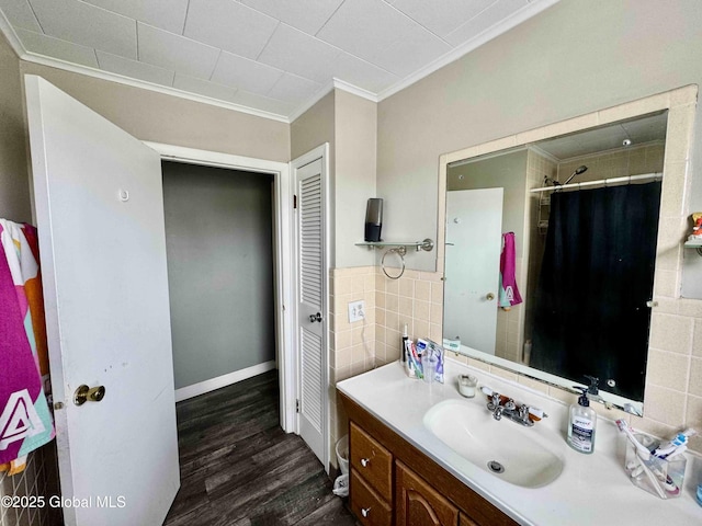 full bath featuring a shower with shower curtain, wood finished floors, vanity, tile walls, and crown molding