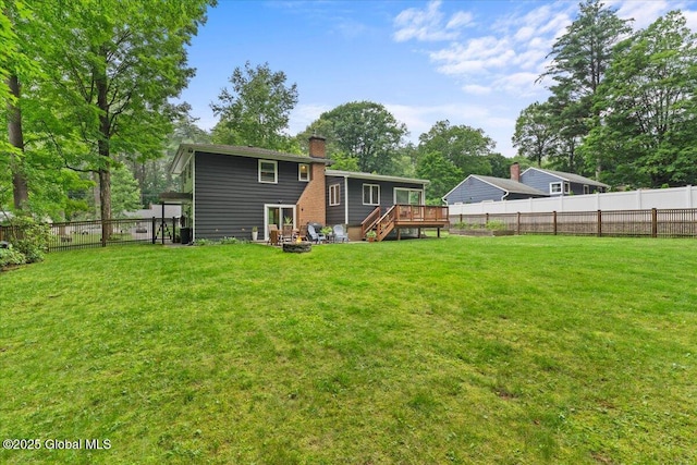 rear view of property with a deck, a fenced backyard, a lawn, and a chimney