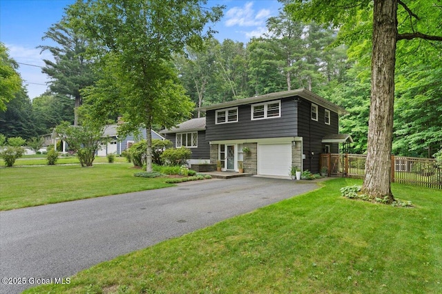 view of front of home featuring driveway, stone siding, an attached garage, fence, and a front lawn