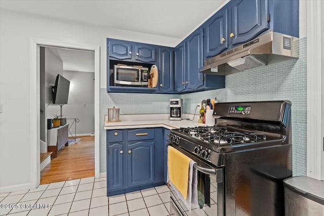 kitchen featuring blue cabinets, stainless steel microwave, black range with gas cooktop, and under cabinet range hood