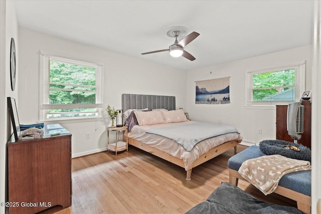 bedroom with ceiling fan, light wood finished floors, multiple windows, and baseboards