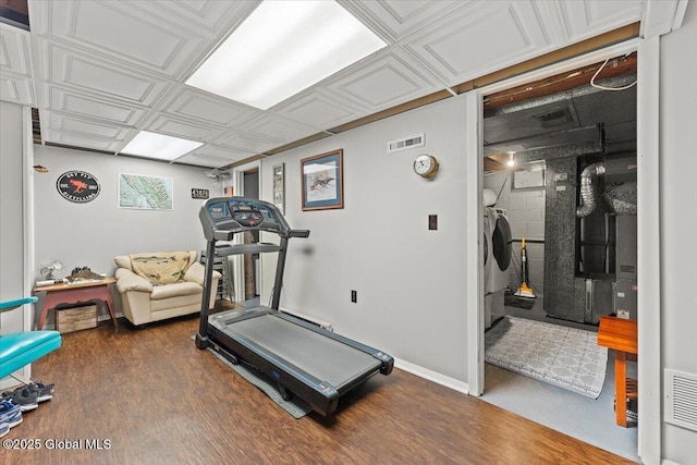 exercise room featuring baseboards, an ornate ceiling, visible vents, and wood finished floors