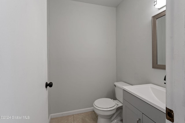 half bath featuring baseboards, vanity, toilet, and tile patterned floors