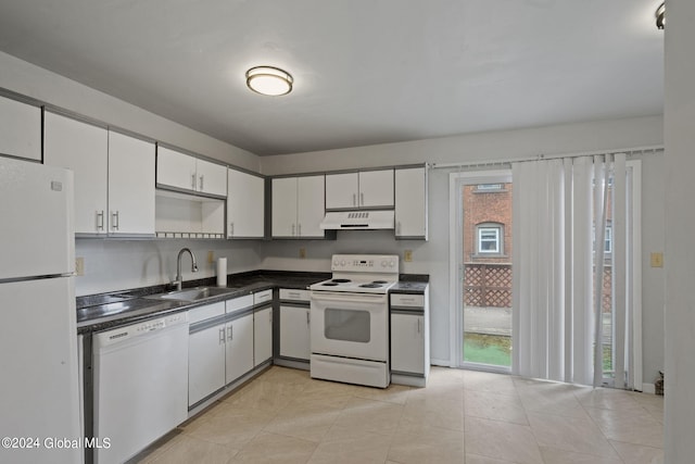 kitchen with white appliances, dark countertops, under cabinet range hood, white cabinetry, and a sink