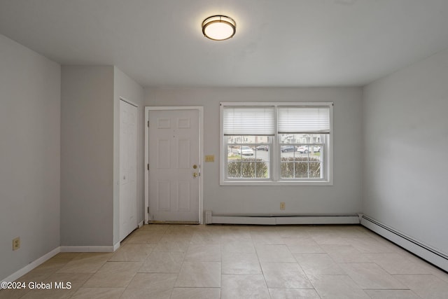 spare room with light tile patterned floors, a baseboard radiator, and baseboards