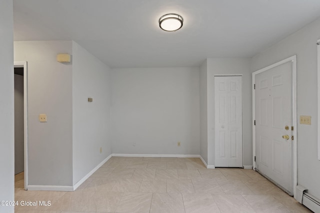 unfurnished room with a baseboard heating unit and baseboards