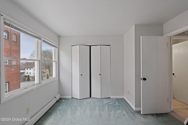 unfurnished bedroom featuring a closet, a baseboard radiator, carpet flooring, and baseboards