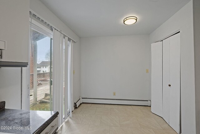 unfurnished bedroom with a baseboard heating unit, access to outside, and a closet