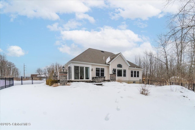 snow covered property with a sunroom and fence