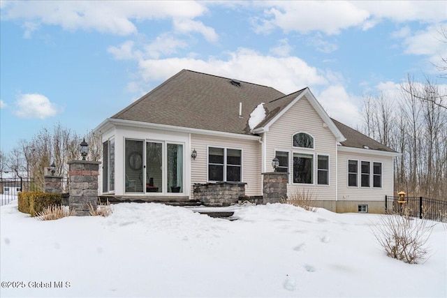 snow covered house featuring fence