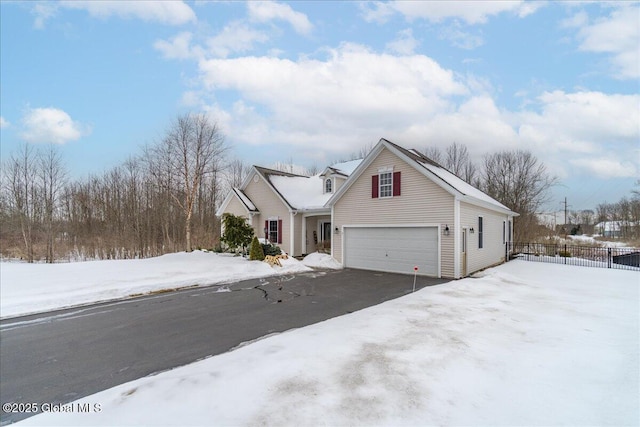 view of front of property featuring aphalt driveway, fence, and an attached garage