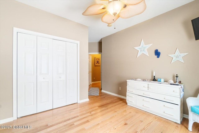 bedroom featuring baseboards, a closet, a ceiling fan, and light wood-style floors