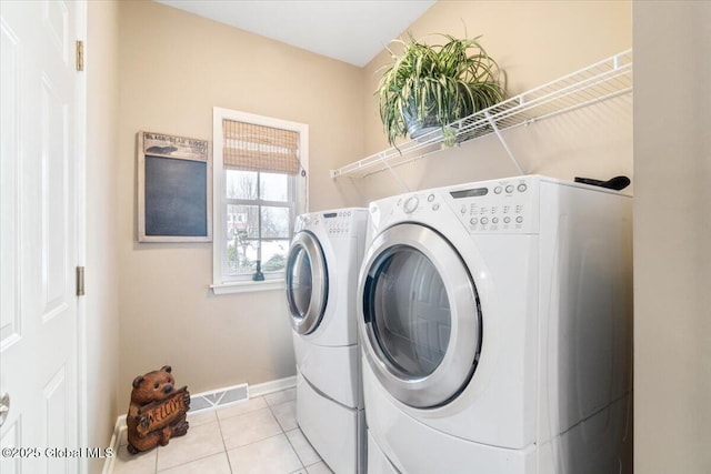 laundry room featuring laundry area, visible vents, baseboards, washing machine and clothes dryer, and light tile patterned flooring