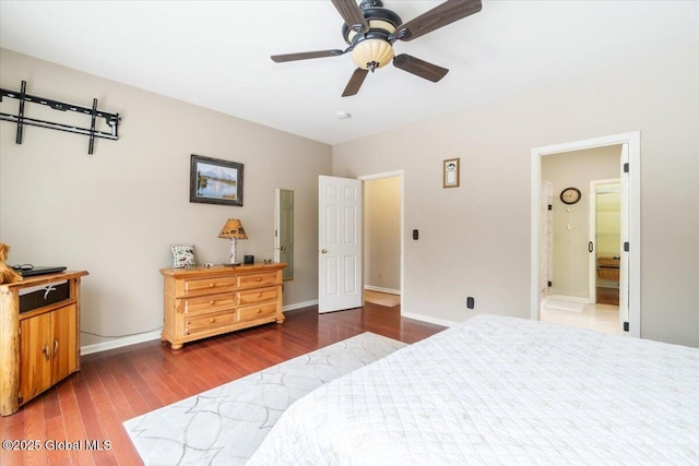 bedroom featuring a ceiling fan, baseboards, wood finished floors, and ensuite bathroom