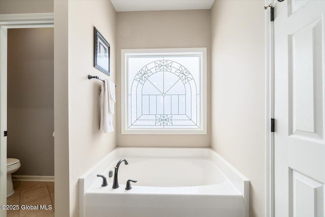 bathroom with tile patterned flooring, a garden tub, and toilet