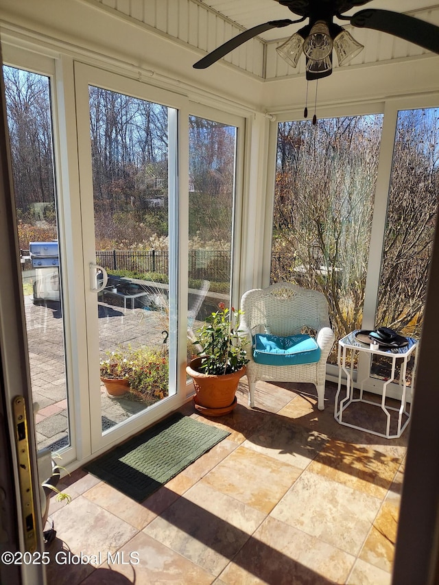 unfurnished sunroom featuring ceiling fan and a wealth of natural light