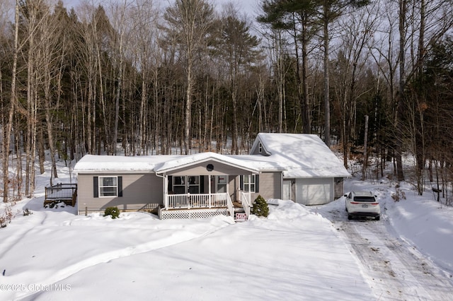 view of front of property with a garage, a porch, and a wooded view