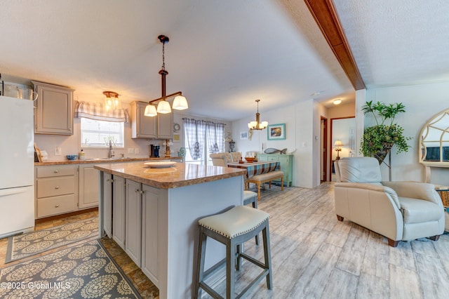 2 S Forty Rd, Hadley, NY 12835 - kitchen featuring open floor plan, freestanding refrigerator, beamed ceiling, a notable chandelier, and a kitchen island