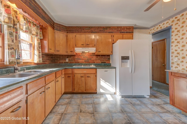 kitchen with white appliances, under cabinet range hood, a sink, ornamental molding, and wallpapered walls