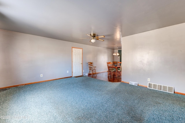 carpeted spare room with ceiling fan, baseboards, and a chandelier