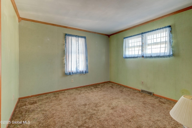 carpeted spare room featuring crown molding and baseboards