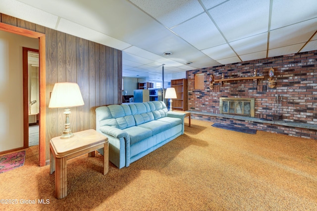 living area featuring carpet floors, a paneled ceiling, wooden walls, and a fireplace