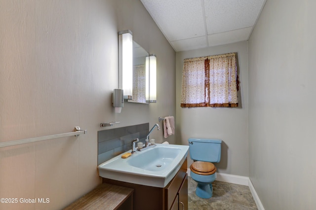 bathroom featuring toilet, a paneled ceiling, vanity, and baseboards