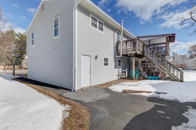 snow covered rear of property with a deck and stairs