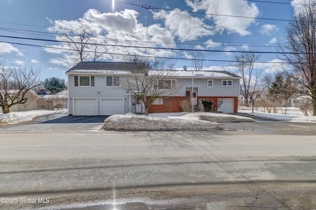 split foyer home with a garage, driveway, and brick siding