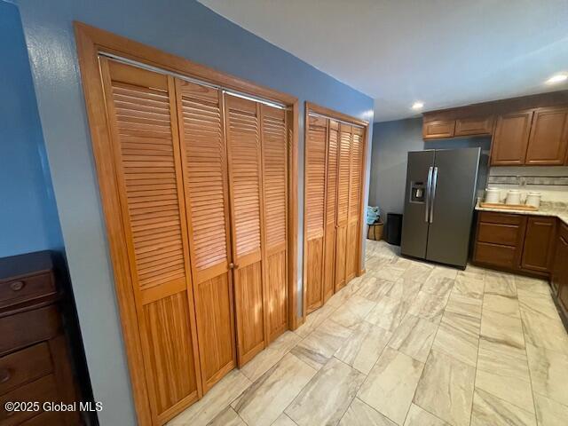 kitchen featuring recessed lighting, light countertops, backsplash, brown cabinets, and stainless steel fridge